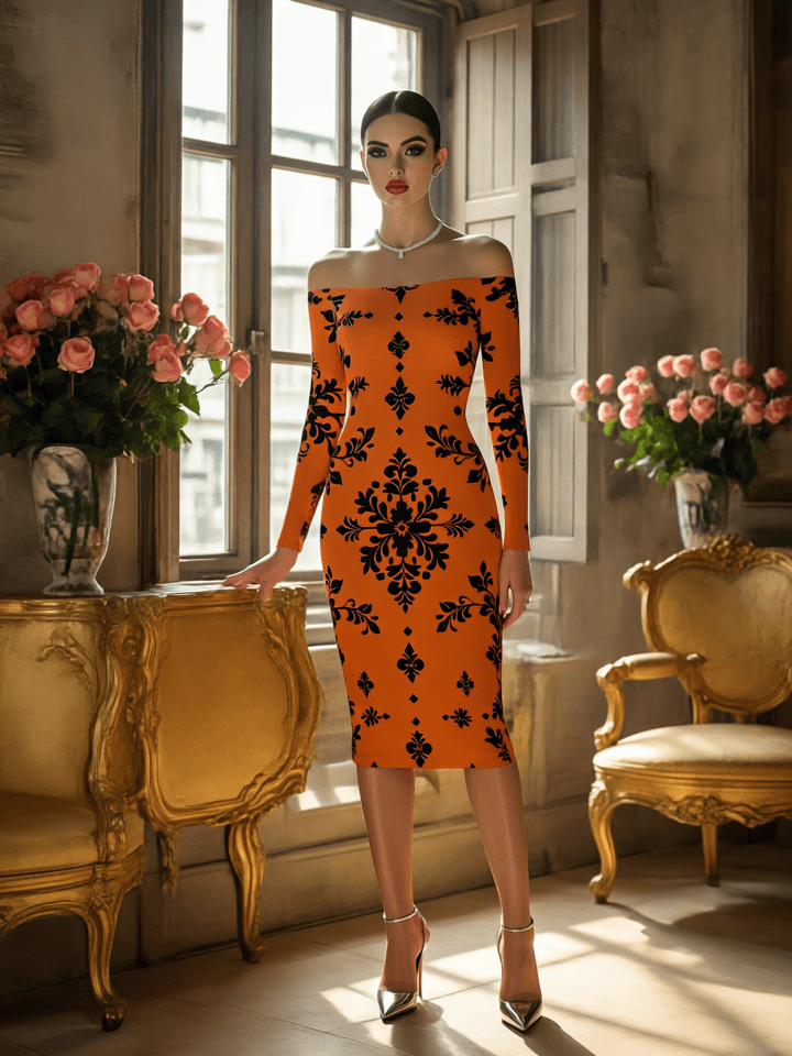 Woman in an orange dress with black floral pattern standing in a stylish room with gold furniture and pink flowers.
