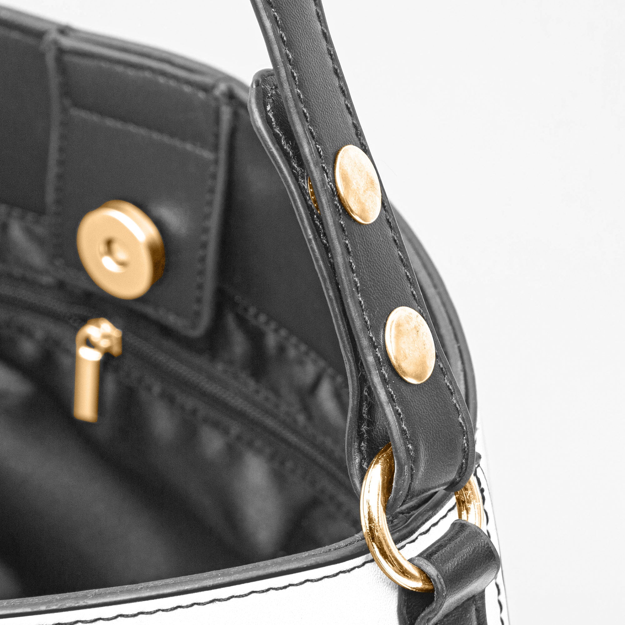Close-up of black leather strap and gold hardware on a brown baroque print bucket handbag