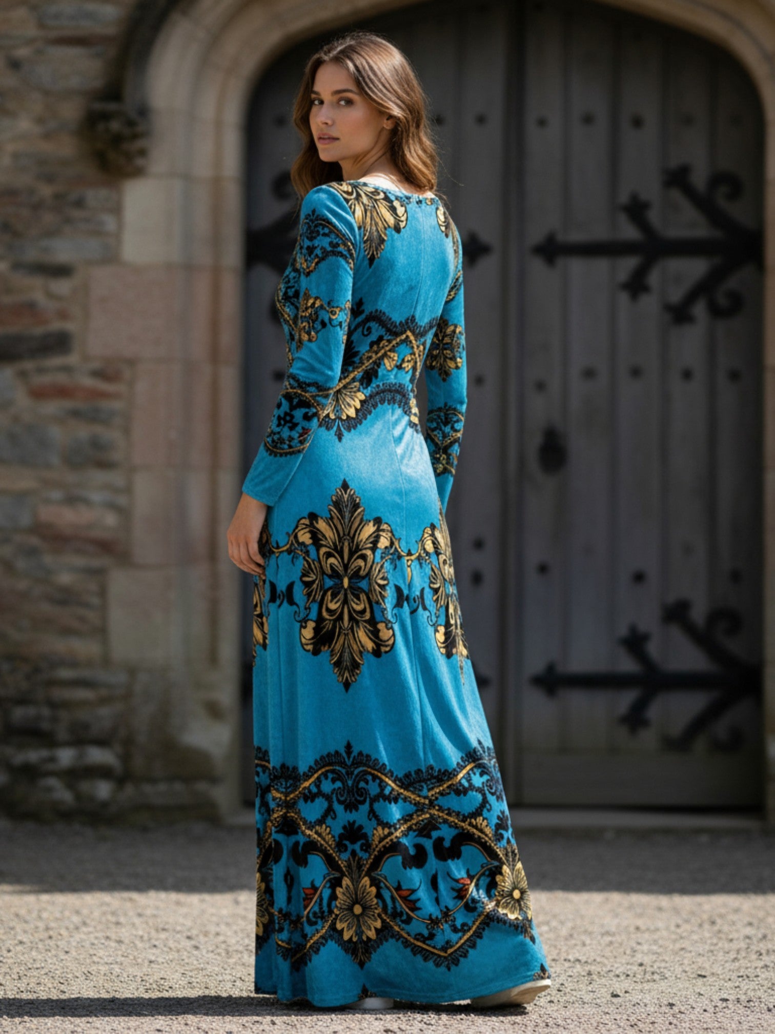 Woman wearing a baroque print velvet maxi dress in blue and gold from Angelic Blessings Shop standing outdoors