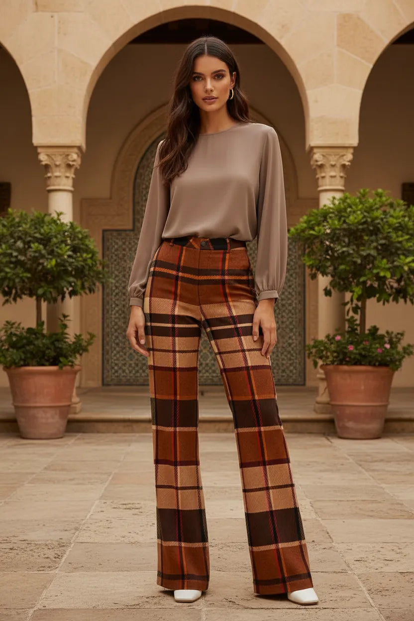 Woman wearing brown tartan wide leg trousers women styled with a taupe blouse in outdoor setting