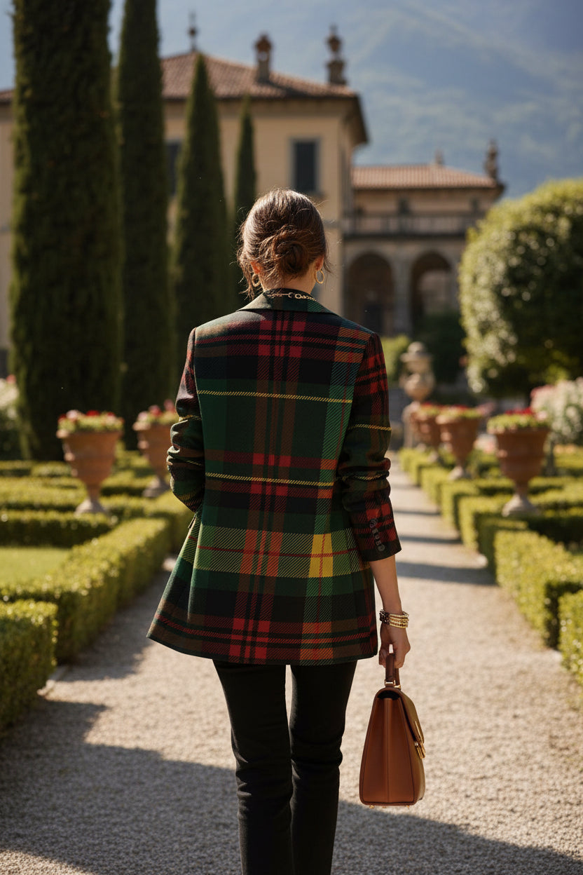 Back view of woman wearing green tartan women's blazer walking in a garden holding a brown handbag