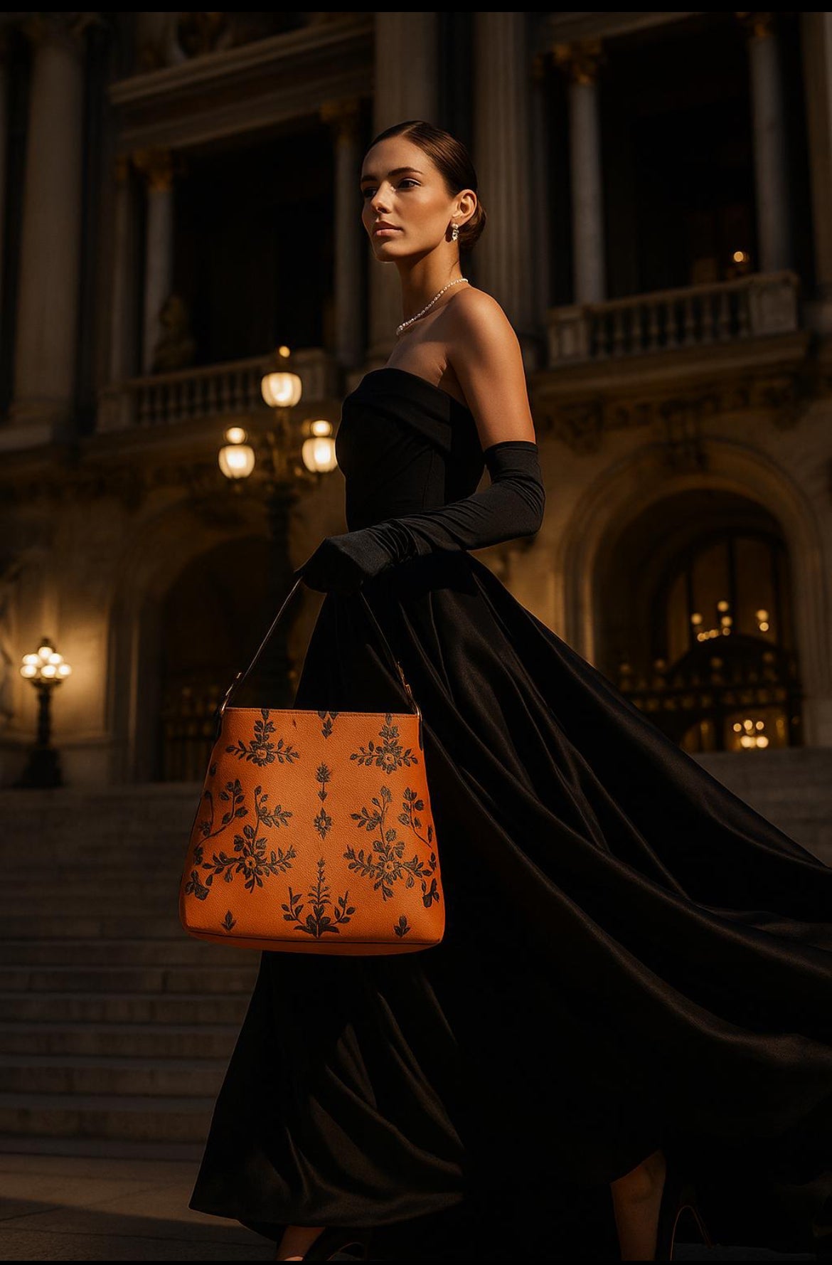 Angelic Blessings Shop orange baroque bucket bag held by woman in elegant black dress at night