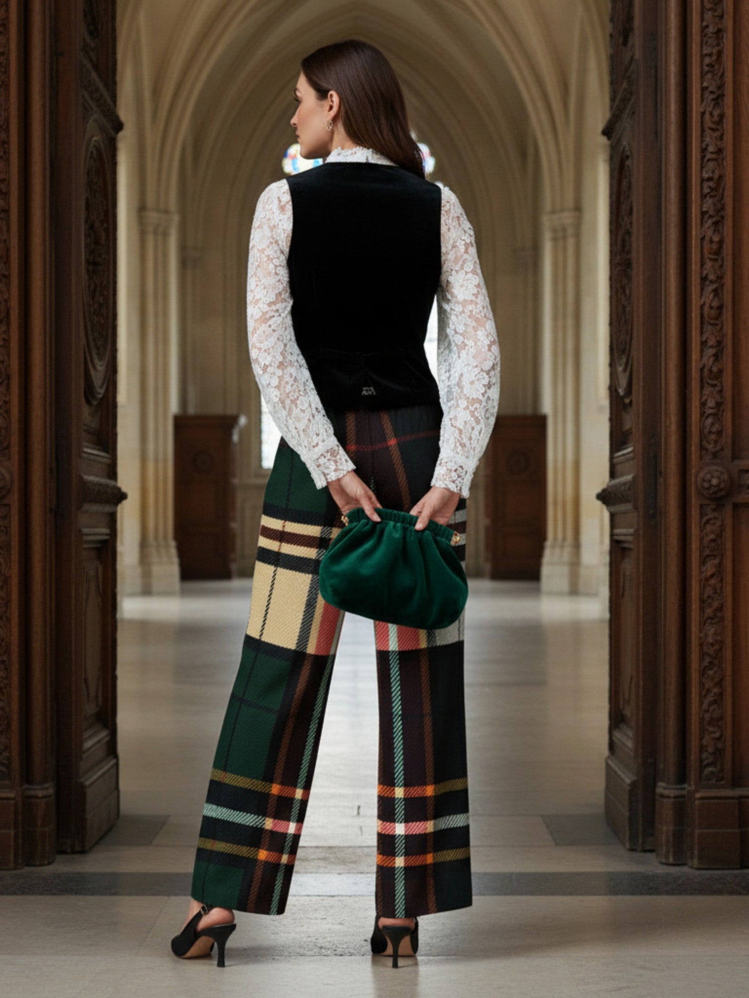 Back view of model wearing women's tartan wide-leg trousers with a black vest and white lace blouse